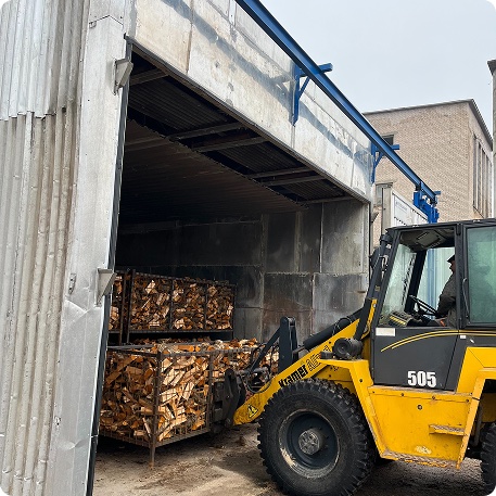 Wheel loader placing crates of firewood into the drying kiln
